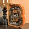 Piggy bank alphabet en bois en forme de lettre, rempli de pièces de monnaie.