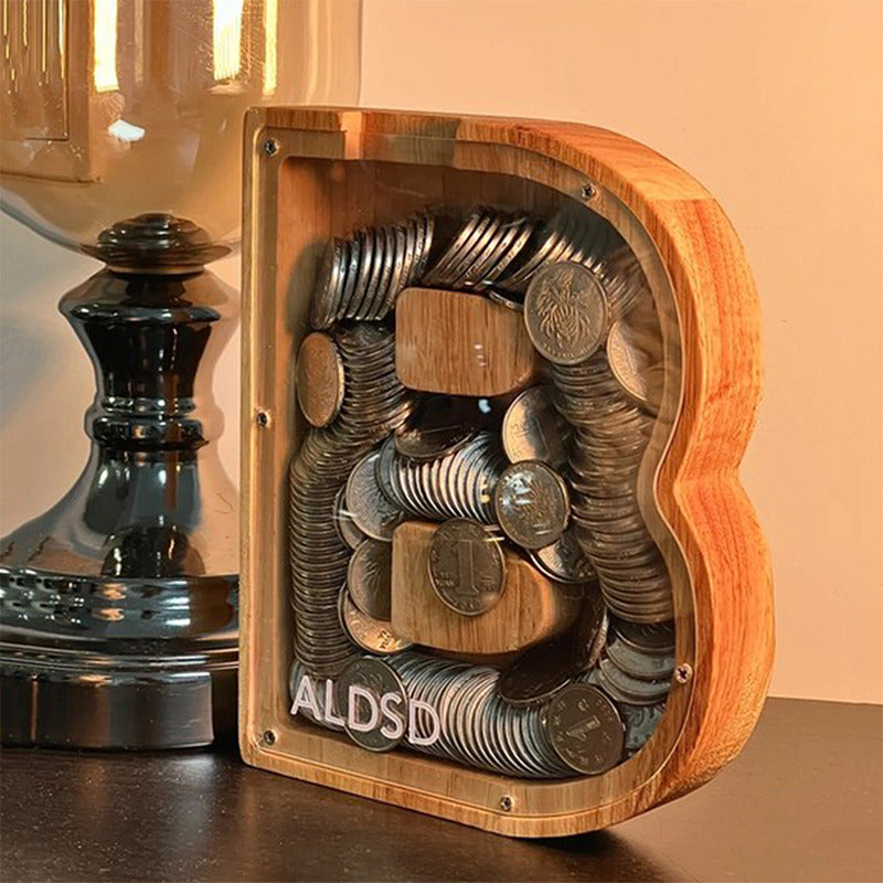 Piggy bank alphabet en bois en forme de lettre, rempli de pièces de monnaie.