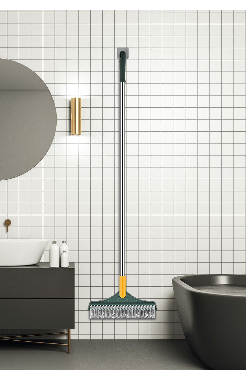 Lange, silber-orange rotierende Bodenreinigungsbürste hängt an einer weißen Fliesenwand über einem dunklen Waschbecken und ei