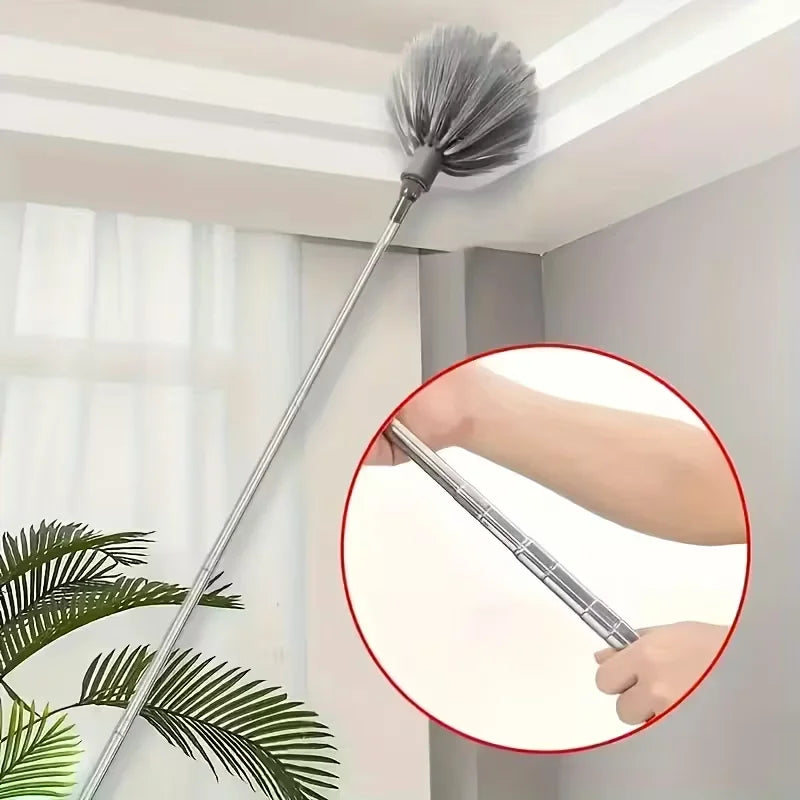 A close-up view of an adjustable length metal cleaning broom hanging on a ceiling, with a hand holding the handle.