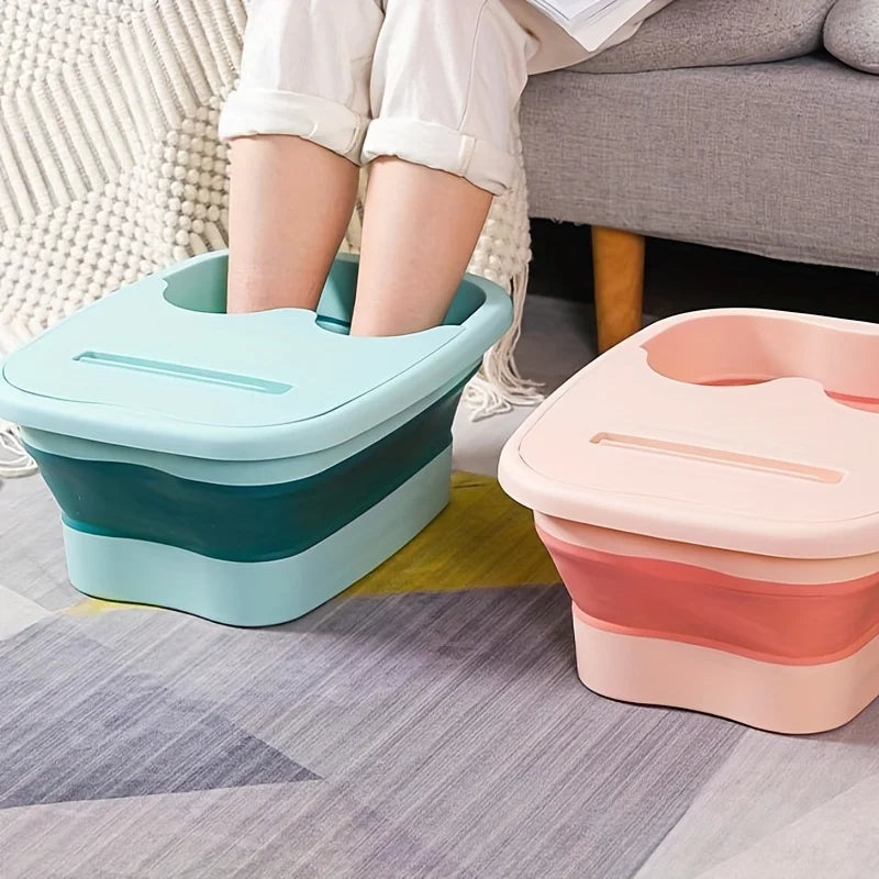Two collapsible foot soak buckets in teal and pink resting on a gray rug next to a person's legs.