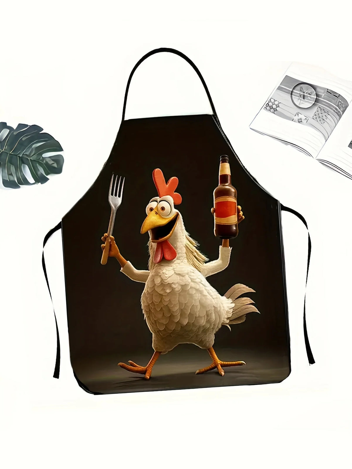 A black apron shaped like a rooster, featuring a cartoon illustration of a proud rooster holding a fork and a bottle.
