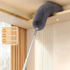 A silver telescopic duster with a fluffy gray head is shown hanging above a cabinet in a modern room.
