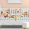 A white crib decorated with a bohemian cotton hanging storage chain featuring various stuffed animal toys.