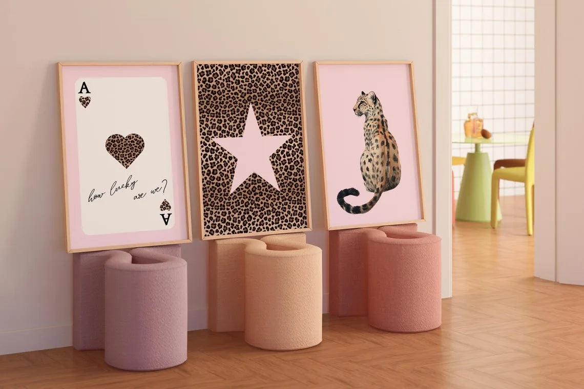 Ein Set aus drei gerahmten Leinwanddrucken mit Leoparden- und Gepardmuster in rosa und goldenen Tönen.