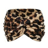 A black and white leopard print elastic knot yoga and fitness headband tied around the head.