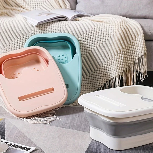 A pink and teal collapsible foot soak bucket is shown resting on a cream knit blanket.