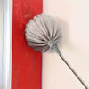 A silver metal cleaning broom leaning against a red vertical surface.