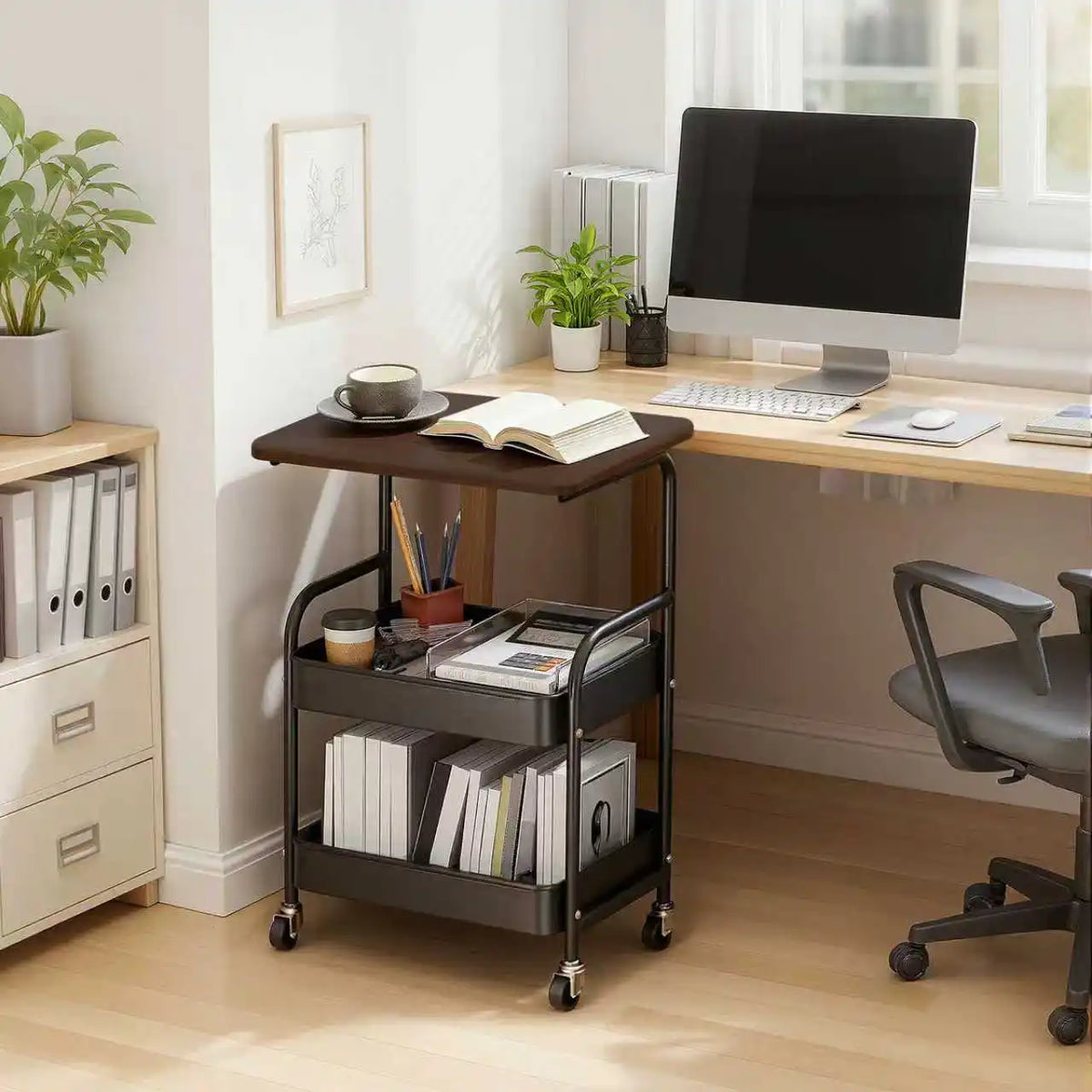 A black 3-tier rolling storage cart with a wooden top and lockable wheels is placed on a light wood desk.