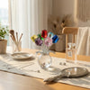 Crystal rose flower figurine in a clear glass vase with colorful petals on a wooden table.
