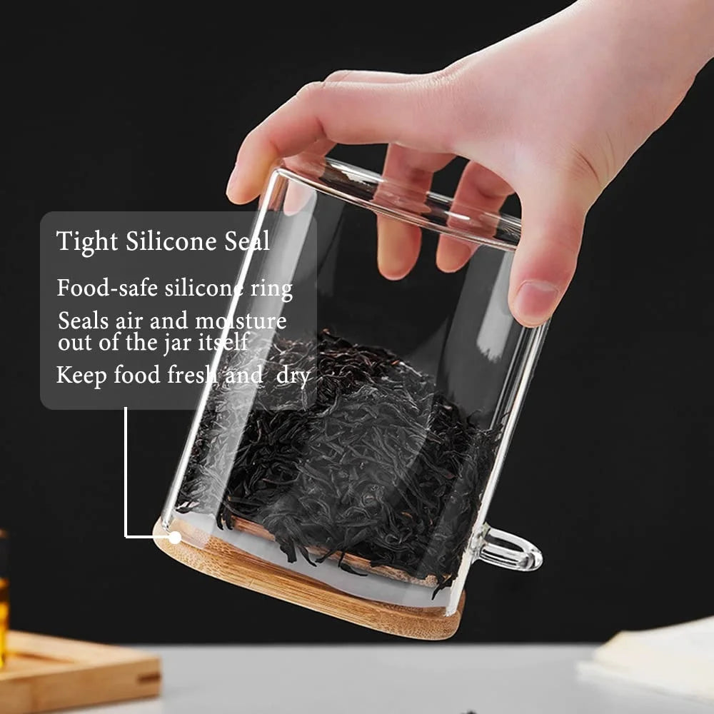 A hand is sealing an airtight glass jar with a silicone seal, showing the jar's dark contents and bamboo lid.