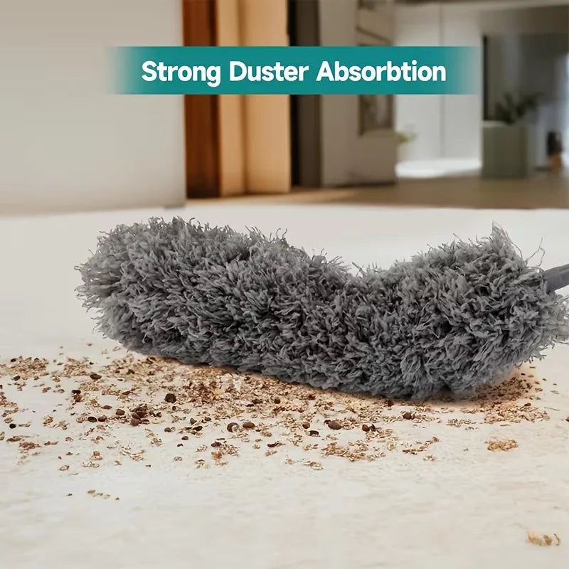 A grey telescopic duster with dense bristles is shown cleaning a white floor.