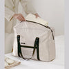 A beige foldable travel duffel bag is shown being held by a person, demonstrating its increased capacity.