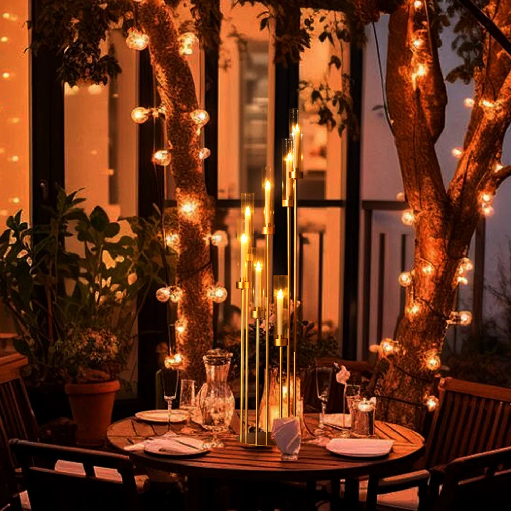 Centro de mesa con candelabro de 7 brazos de oro, exhibido en una mesa de madera al aire libre.