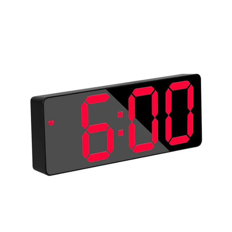 A black digital alarm clock displaying 6:00 with red LED numerals.