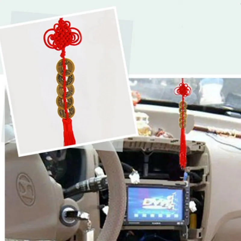Handmade red knot feng shui coins for prosperity displayed in a car interior.