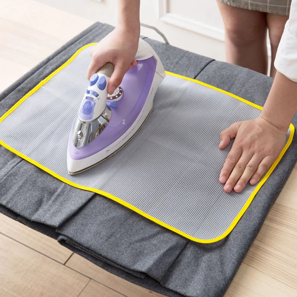A hand is ironing a garment on a gray ironing board using a purple high-temperature protection iron.