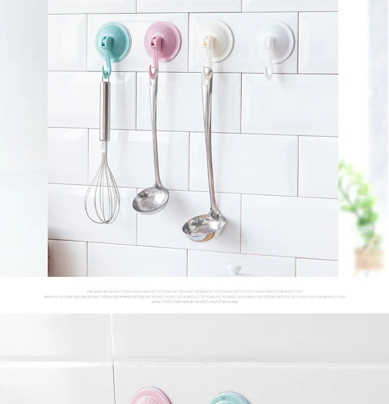 A set of silicone spoons with suction cup hooks hanging on a white tiled wall.