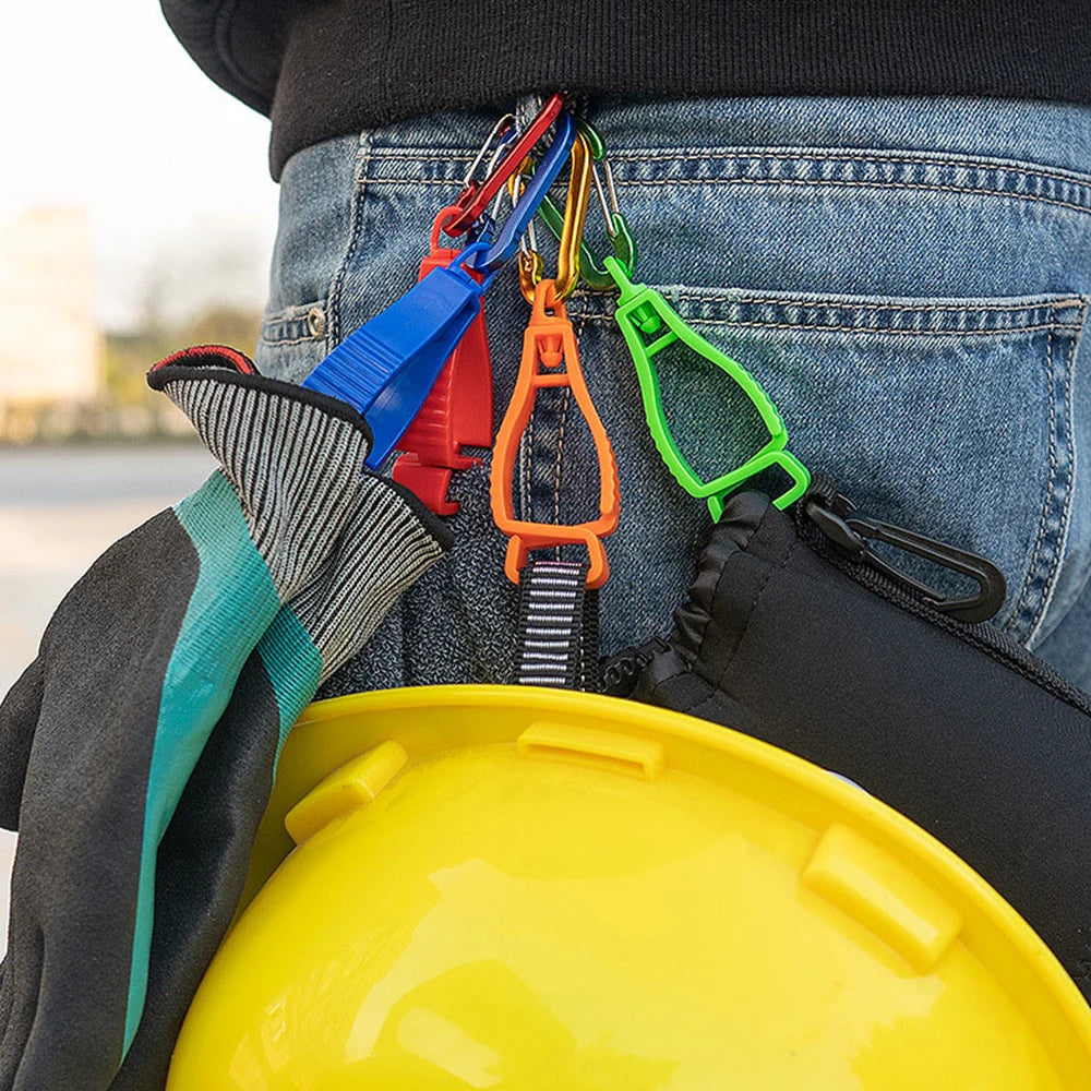 A close-up of a durable glove clip with an ergonomic buckle attached to a denim pocket and a yellow hard hat.