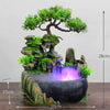 A resin water fountain featuring a mossy rock structure and green foliage with purple illuminated water.