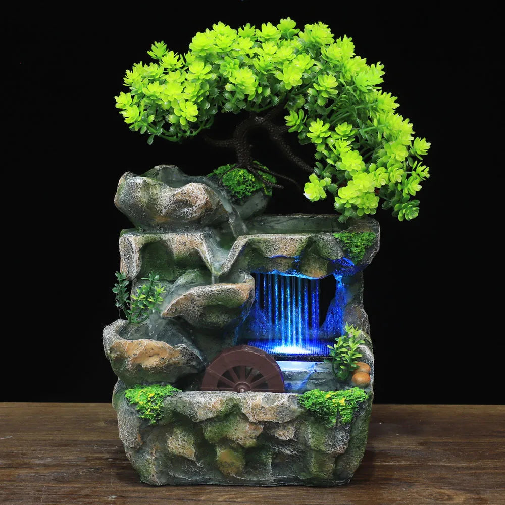 A resin water fountain featuring mossy rocks and vibrant green foliage with a blue water cascade.