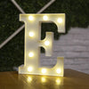A white illuminated letter E made of LED lights resting on a wooden surface.