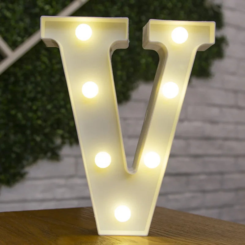 A white alphabet letter V made of LED lights illuminating a brick wall background.