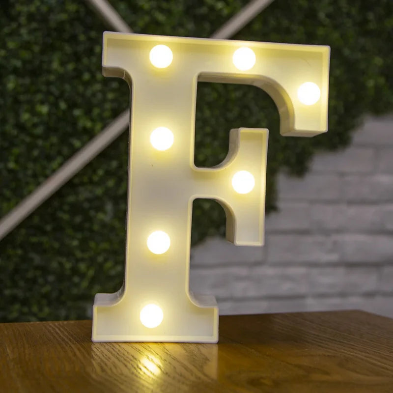 A white alphabet letter F made of LED lights illuminating a green hedge background