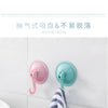 Pink and teal suction cup hooks for waterproof grip on a white wall