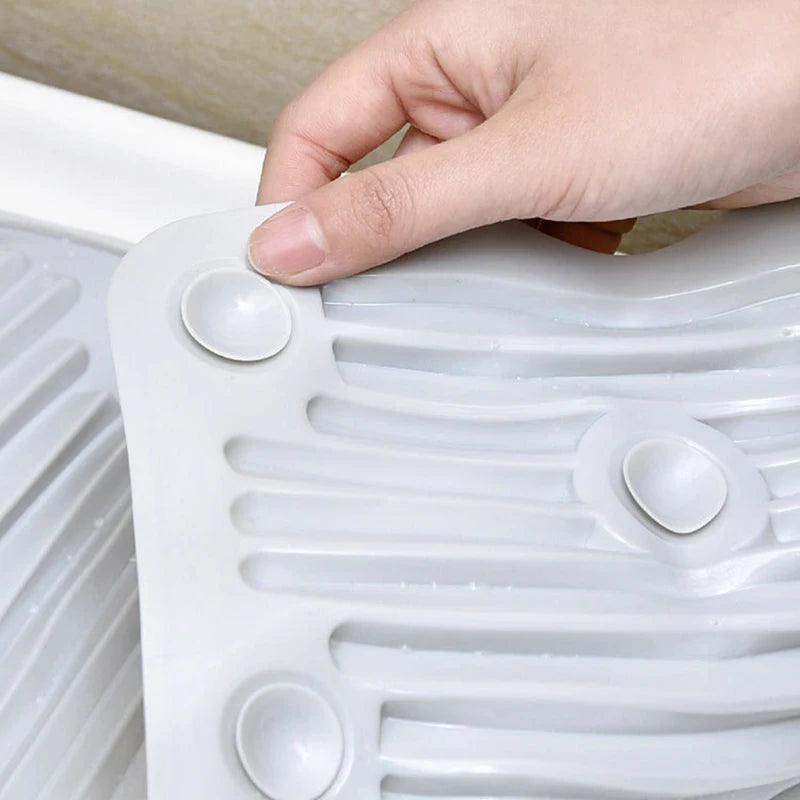 Una mano toca una tabla de lavar plegable de silicona blanca con estrías e indentaciones circulares.
