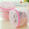 A pink reusable mesh bag for washing lingerie, shown on a white surface.