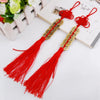 Handmade red knot feng shui coins with gold accents and tassels displayed on a white background.