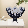 A black deer antler shaped toilet paper holder and storage rack with white rolls on a white table.