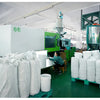 White leakproof food grade storage buckets stacked on a green shelf in a factory setting.