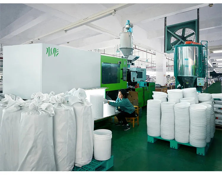 White leakproof food grade storage buckets stacked on a green shelf in a factory setting.