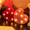 Two heart-shaped LED lights, one red and one pink, are displayed on a dark surface.