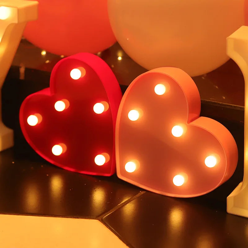 Two heart-shaped LED lights, one red and one pink, are displayed on a dark surface.