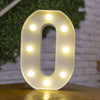 A white, illuminated number zero sign with LED lights shaped like dots, resting on a wooden surface.