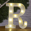 A white letter R made of LED lights is displayed on a wooden surface.