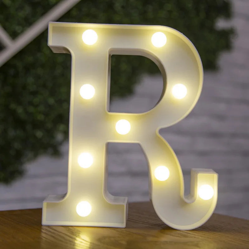 A white letter R made of LED lights is displayed on a wooden surface.