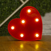 A bright red heart-shaped light decoration with multiple illuminated LED lights on a wooden surface.