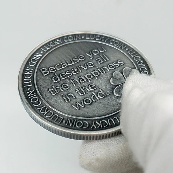Primer plano de una moneda conmemorativa plateada que dice: Porque mereces toda la felicidad del mundo.