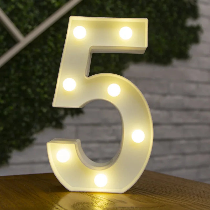 A glowing white LED light number 5 is displayed on a wooden surface against a blurred green background.
