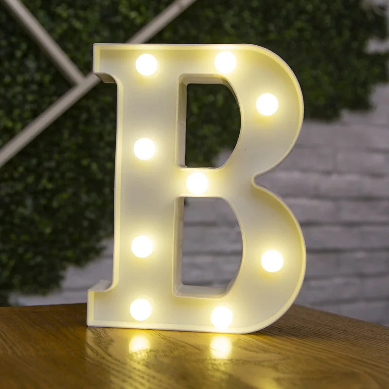 A glowing white letter B made of LED lights sitting on a wooden surface.
