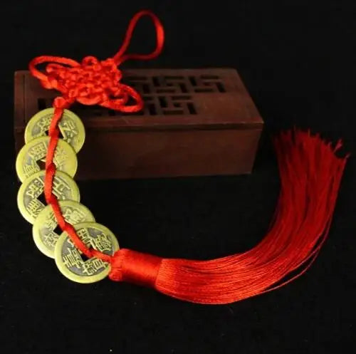 Handmade red knot feng shui coins for prosperity with a red cord and wooden box.