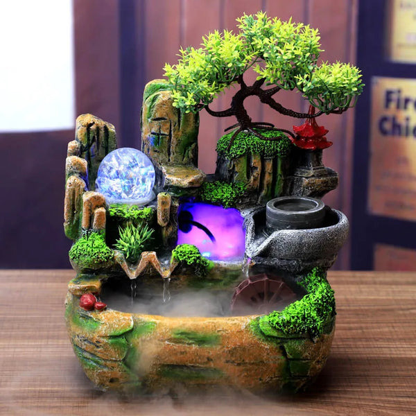 A resin water fountain featuring mossy rocks, a blue crystal, and green foliage on a wooden surface.
