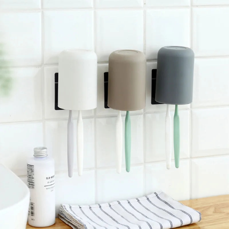 A multi-use wall mounted organizer holding three different colored cups or toothbrushes.
