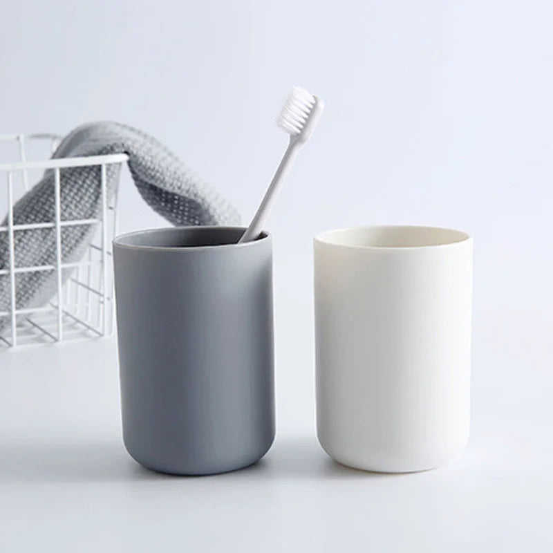 A gray cup and a white cup with a brush are displayed on a white surface.