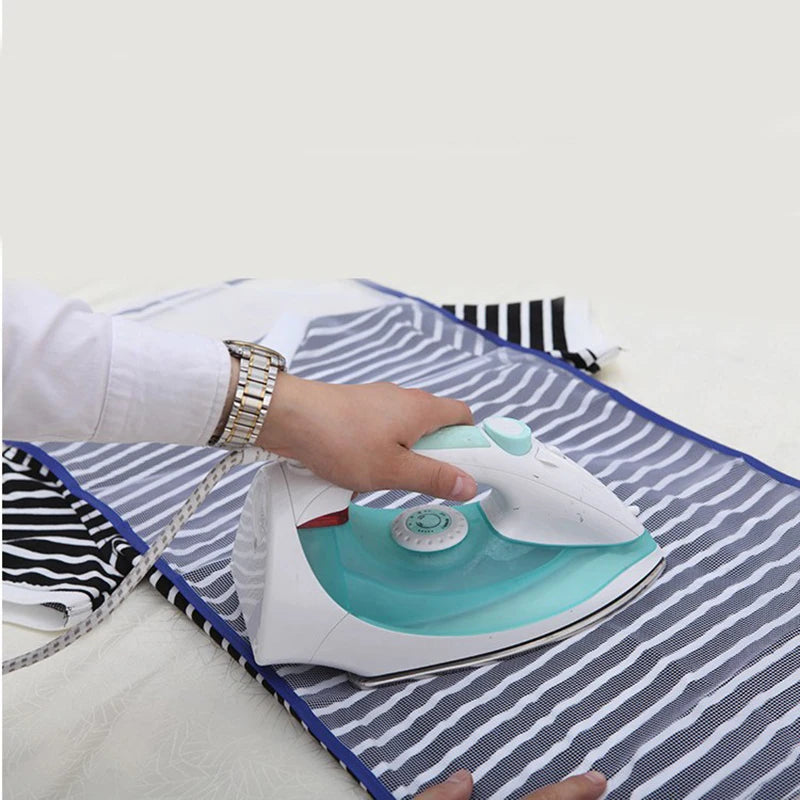 A hand is placing a white iron with a light blue heating plate onto a striped ironing protection mesh pad.