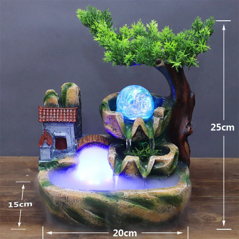 A resin water fountain featuring a tree, a house structure, and a glowing blue orb on a mossy base.